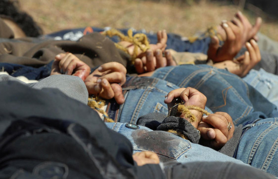 Men with their hands tied behind their backs lie dead in a field near